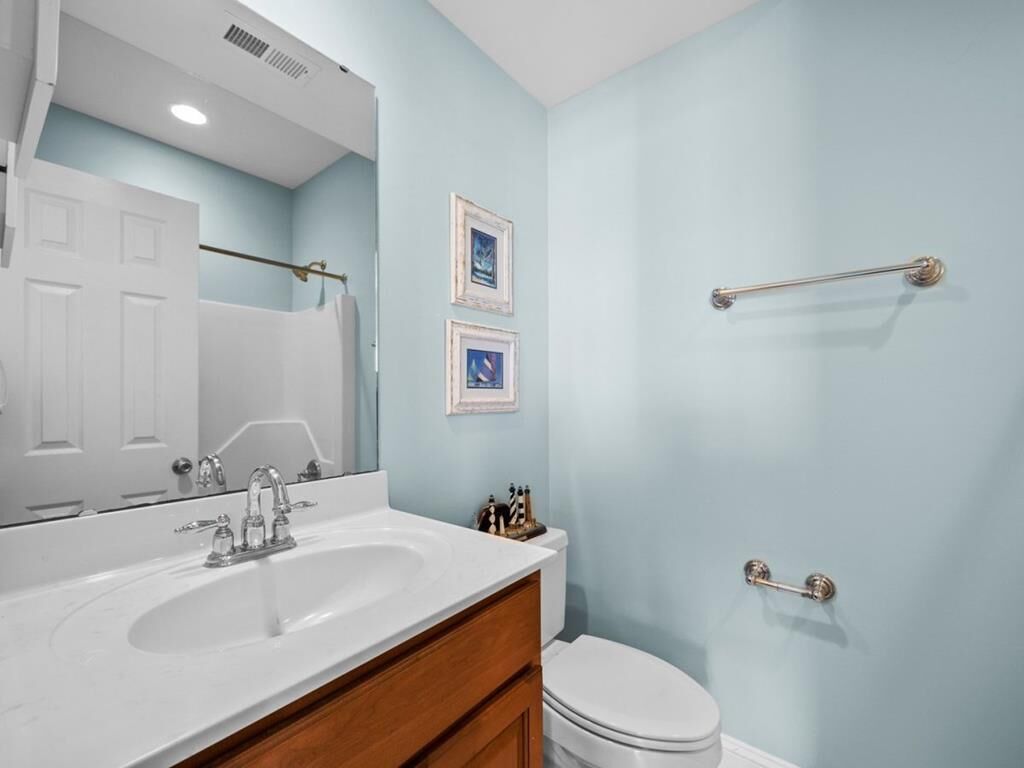Une salle de bain avec un lavabo blanc, un miroir, des toilettes et un porte-serviettes.