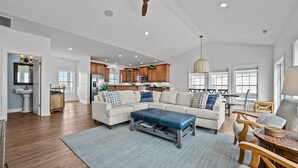 A spacious living room with a sectional sofa, a coffee table, and a dining area with wooden furniture.