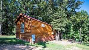 A wooden cabin with a window, a door, and a small porch area. - PineCone: Sleep 5, Tiny Cabin, Pet, Near Lake/Park (Broken Bow)