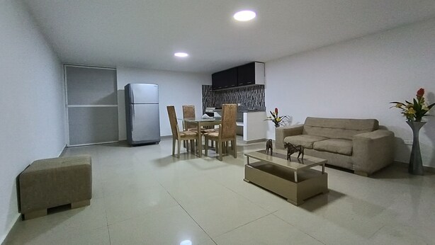 A modern living room with a sofa, coffee table, and dining area. - Ayenda Brisas del Rio (Barranquilla)