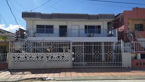 A two-story building with a gated entrance, a balcony on the upper floor, and a staircase to the right. - Ayenda Brisas del Rio (Barranquilla)