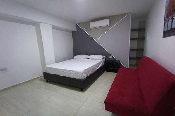 A bedroom with a bed, a red sofa, and a staircase. - Ayenda Brisas del Rio (Barranquilla)