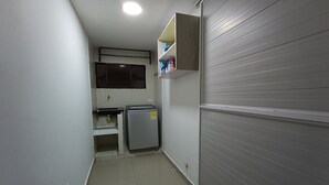 A narrow hallway with a refrigerator, a small sink, and a shelf with bottles. - Ayenda Brisas del Rio (Barranquilla)