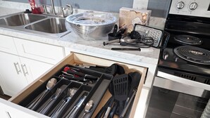 A kitchen with a drawer organizer containing utensils, a sink, a stove, and a box of hand mixer. - Gorgeous New 1 bd condo - 5 Min to Branson Landing (Branson)