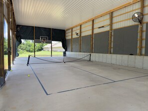 An indoor tennis court with a net, a basketball hoop, and a fan. - Gorgeous New 1 bd condo - 5 Min to Branson Landing (Branson)
