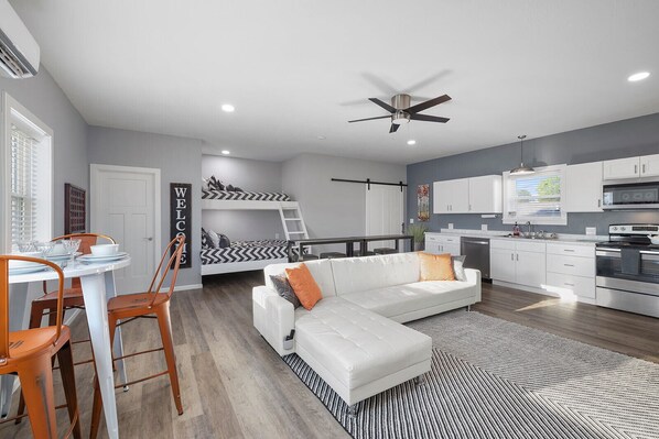 A modern apartment with a dining area, a living room with a sofa, a kitchen, and a bunk bed. - Gorgeous New 1 bd condo - 5 Min to Branson Landing (Branson)