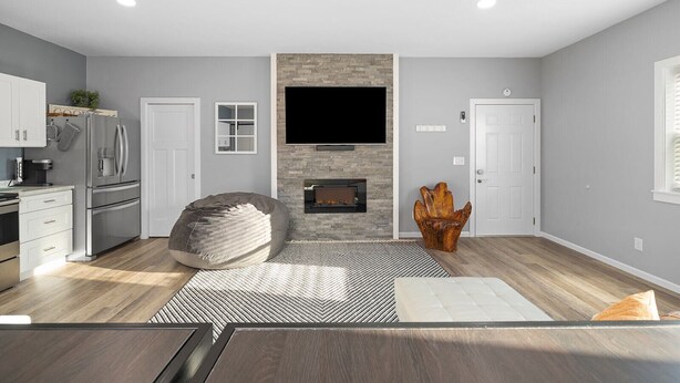 A modern living room with a kitchen, a fireplace, and a large TV. - Gorgeous New 1 bd condo - 5 Min to Branson Landing (Branson)