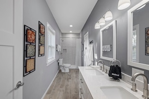 A modern bathroom with a walk-in shower, a toilet, a sink with a vanity, and framed artwork on the walls. - Gorgeous New 1 bd condo - 5 Min to Branson Landing (Branson)