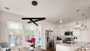 Una cocina moderna con armarios blancos, electrodomésticos de acero inoxidable y una mesa de comedor de madera.