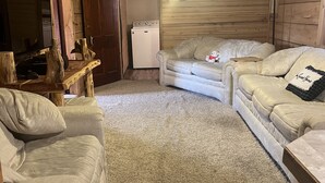 Une pièce chaleureuse avec deux canapés beiges, une table en bois, un ventilateur de plafond et un lave-linge.