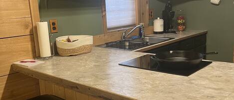 A kitchen with wooden cabinets, a marble countertop, a black stove, and two black stools.