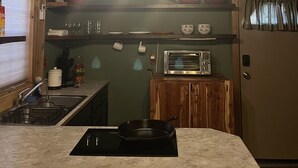Une cuisine équipée d’un plan de travail, d’un évier, d’une cuisinière, d’un four à micro-ondes et de luminaires suspendus.