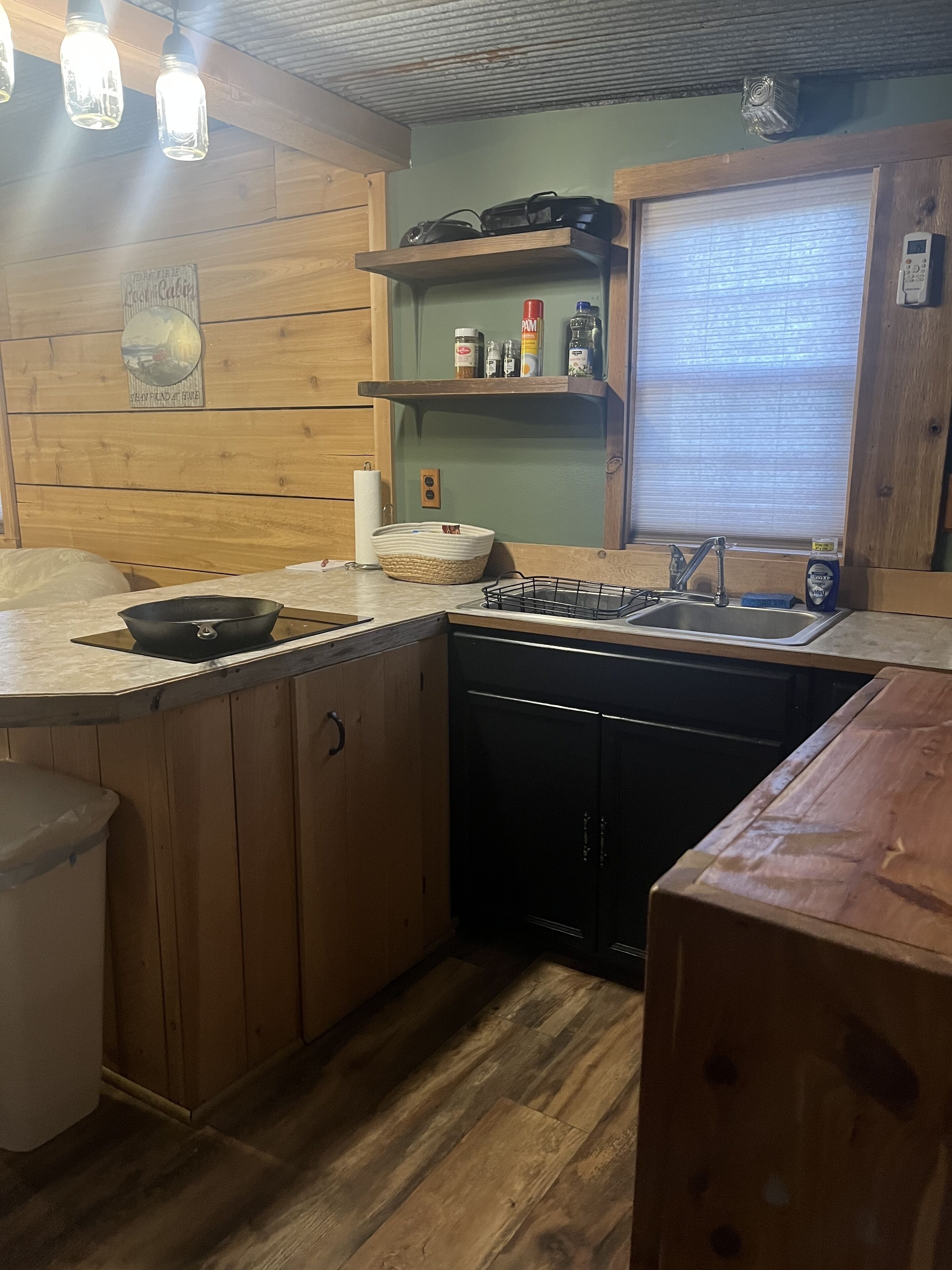 Una cocina compacta con armarios de madera, estufa integrada y un lavamanos.
