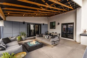 An outdoor living area with a fire pit, sofas, and a dining table.