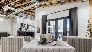Un salon moderne avec un canapé d’angle, une table basse et une cuisine en arrière-plan.