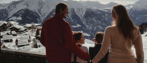 A group of people standing by a window overlooking a snowy mountain landscape.
