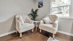 Een kamer met twee fauteuils, een tafeltje en een plant in pot.