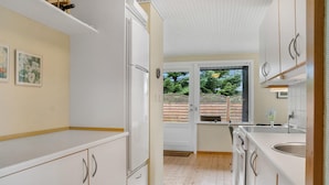 Una cocina compacta con gabinetes blancos, horno empotrado y ventana con vista a una terraza de madera.