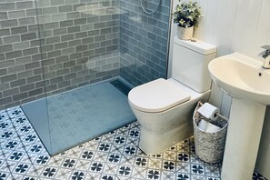 Une salle de bain avec douche, toilettes, lavabo et un carrelage décoratif.
