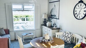 Uma sala de estar acolhedora com uma mesa redonda de madeira, um sofá e um relógio na parede.