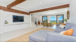 Relax in this spacious living area with a high ceiling, large window, and comfortable sofa.