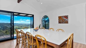Enjoy meals in this dining area with a large table and six chairs, surrounded by a high ceiling and a large window offering a panoramic view.