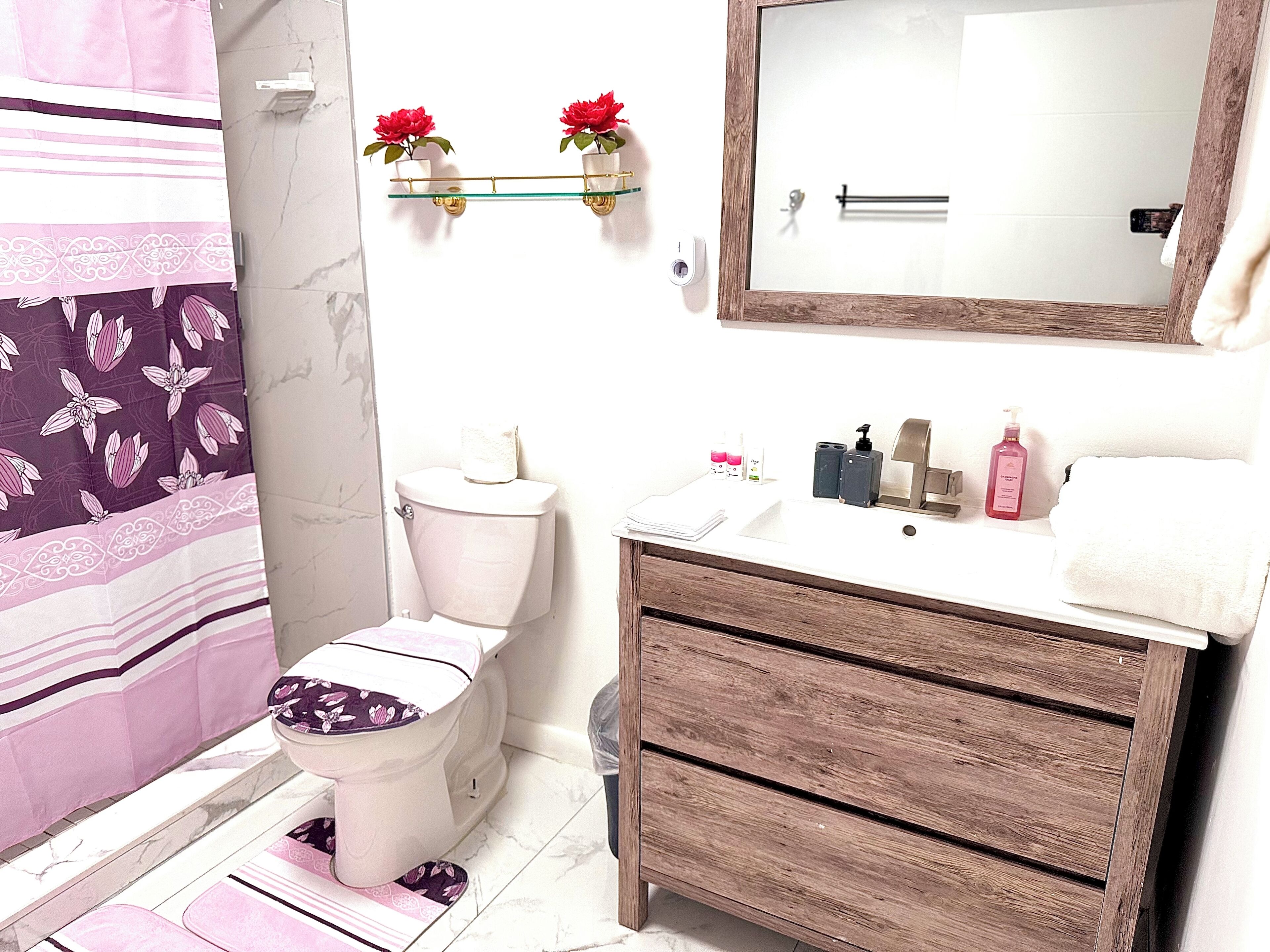 Une salle de bain comprenant des toilettes, un lavabo, un miroir et un espace douche.