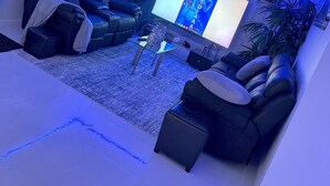 Een woonkamer met een donker leren bank, een glazen salontafel en een flatscreen televisie.