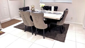 Een eetgedeelte met een marmeren tafel, zwarte bekleden stoelen en een decoratief middelpunt.