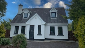A two-story house with a gabled roof, a front door, and two windows on the upper floor. - Burren Seaside Lodge (Ballyvaughan)