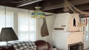 Una sala de estar con sofá de cuero, lámpara colgante y chimenea de ladrillo.