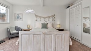 Un dormitorio con una cama, dos mesitas de noche, un armario y una ventana.