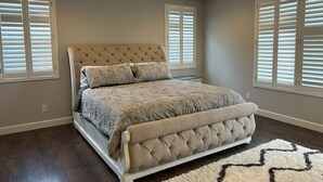 Ein Schlafzimmer mit einer gepolsterten Kopfteile, einem großen Bett und einem gemusterten Teppich.