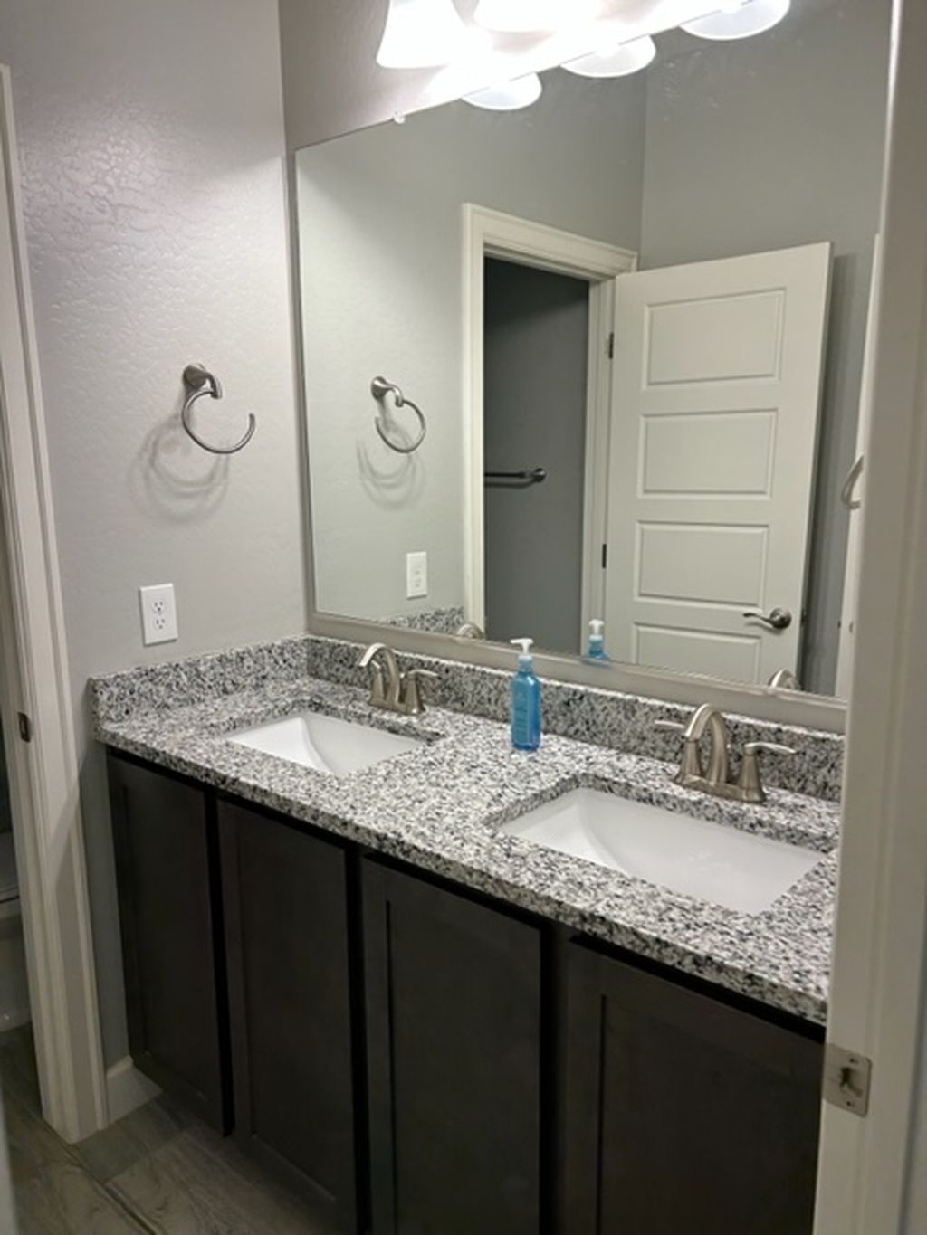 Un baño con dos lavamanos, armarios oscuros, un espejo y una puerta.