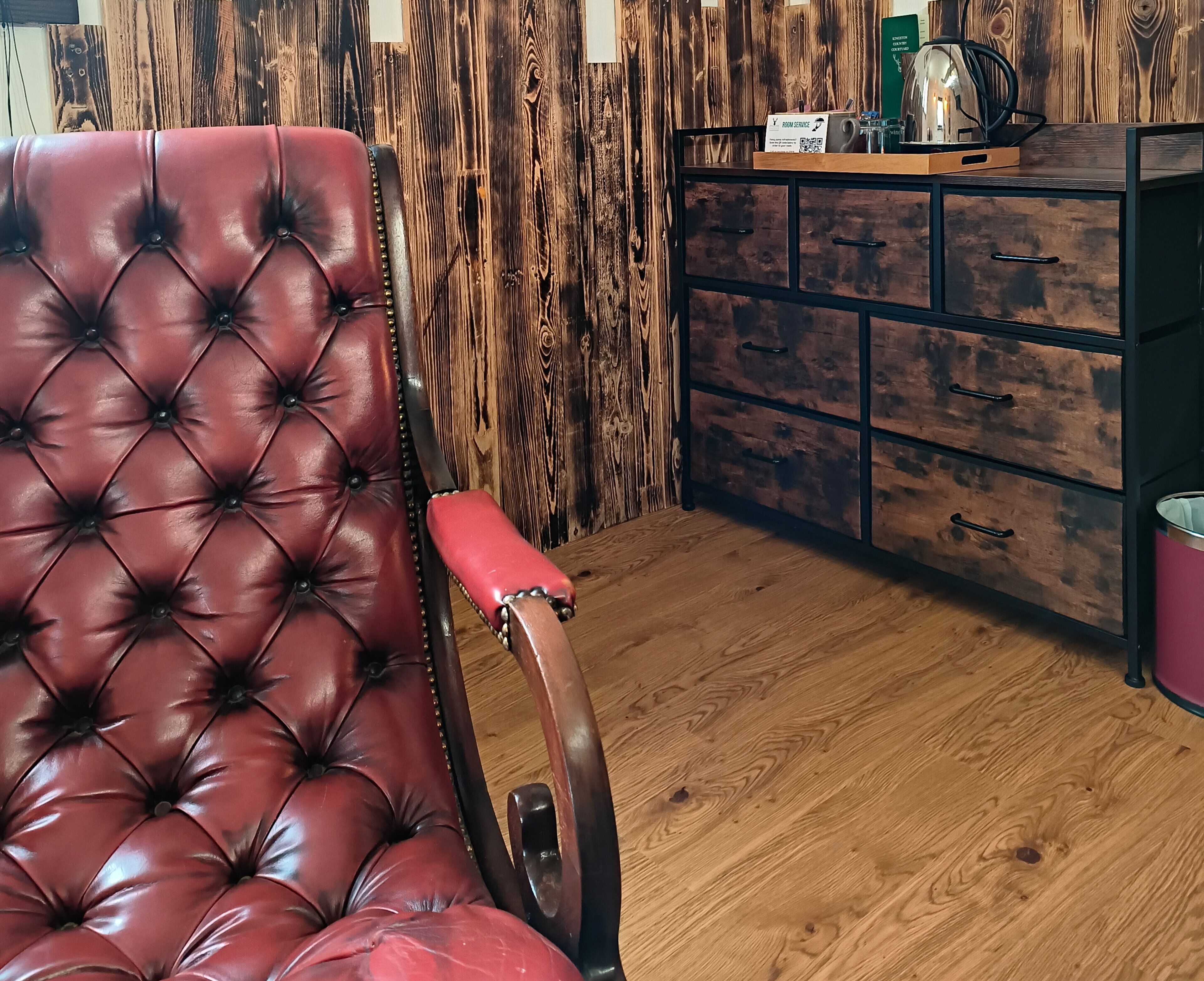 Ein roter Ledersessel, eine Holzkabine mit Schubladen und ein Holzboden.