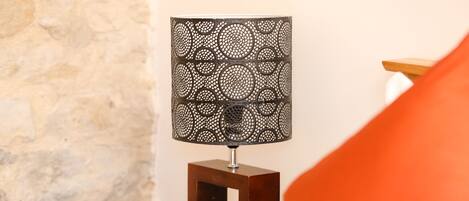 A wooden bedside table with a square mirror and a decorative lamp with a circular pattern.