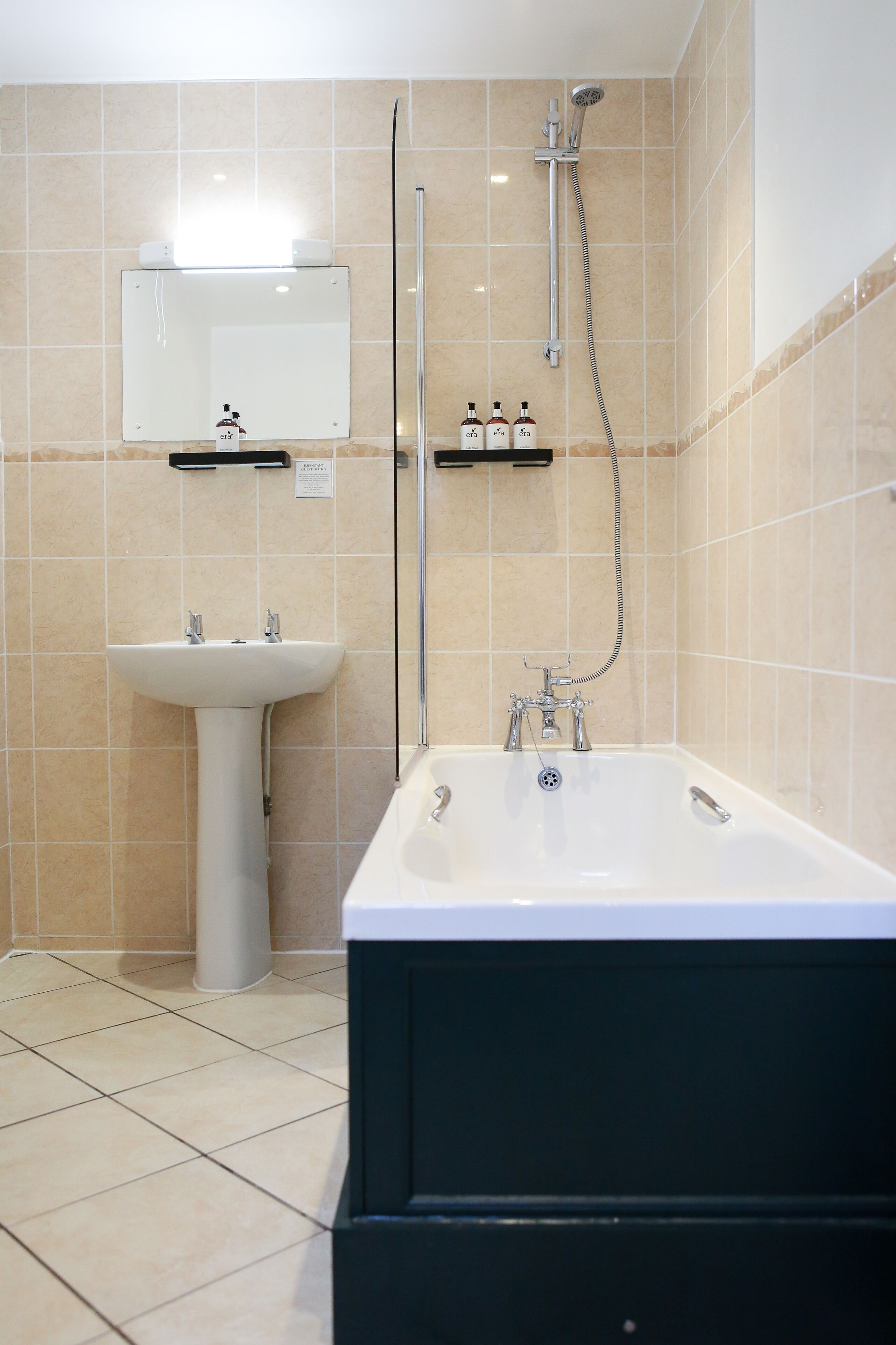 A bathroom with a sink, mirror, and bathtub.