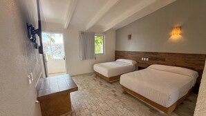 Een hotelkamer met twee bedden, een houten hoofdbord, een klein tafeltje en een televisie aan de muur.