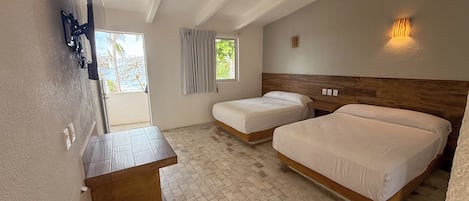 A hotel room with two beds, a wooden headboard, a small table, and a wall-mounted TV.