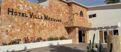 Hotel Villa Mexicana with a stone facade, a clear entrance, and cacti in the landscaping.