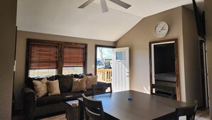 Un coin repas avec une table et des chaises, un ventilateur de plafond et une horloge au mur.