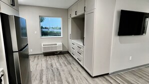 A modern kitchen with a built-in refrigerator, white cabinets, and a window offering a view of the outdoors.
