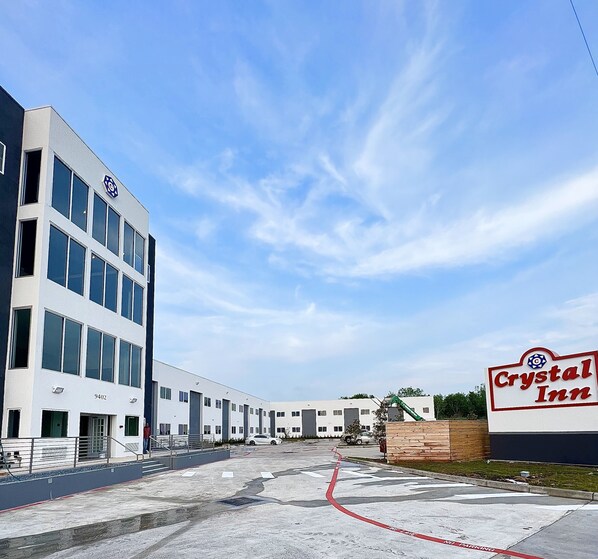 A hotel named Crystal Inn with a modern building, a parking lot, and a clear blue sky. - Crystal Inn Missouri City (Houston)
