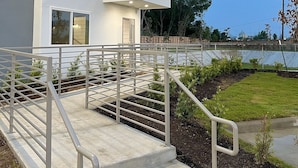 A modern building with a flat roof, a balcony, and a staircase leading to the entrance.