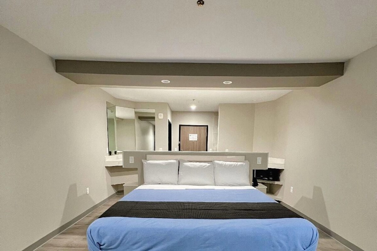 A modern bedroom with a large bed, a bedside table, and a mirror.