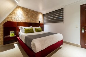 A hotel room with a stone accent wall, a bed with a red headboard, and a window with blinds. - Ayenda 1084 Palacio Real (Bogotá)