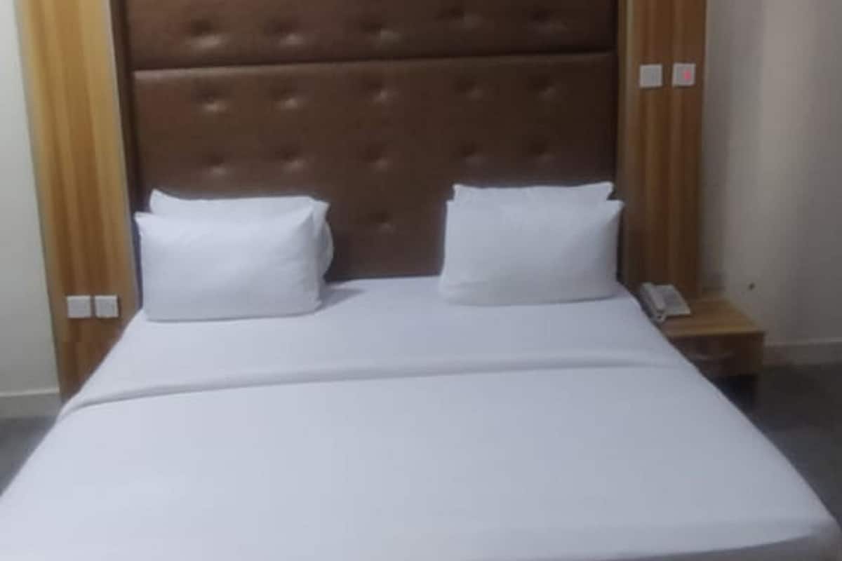 A double bed with a wooden headboard and two white pillows.
