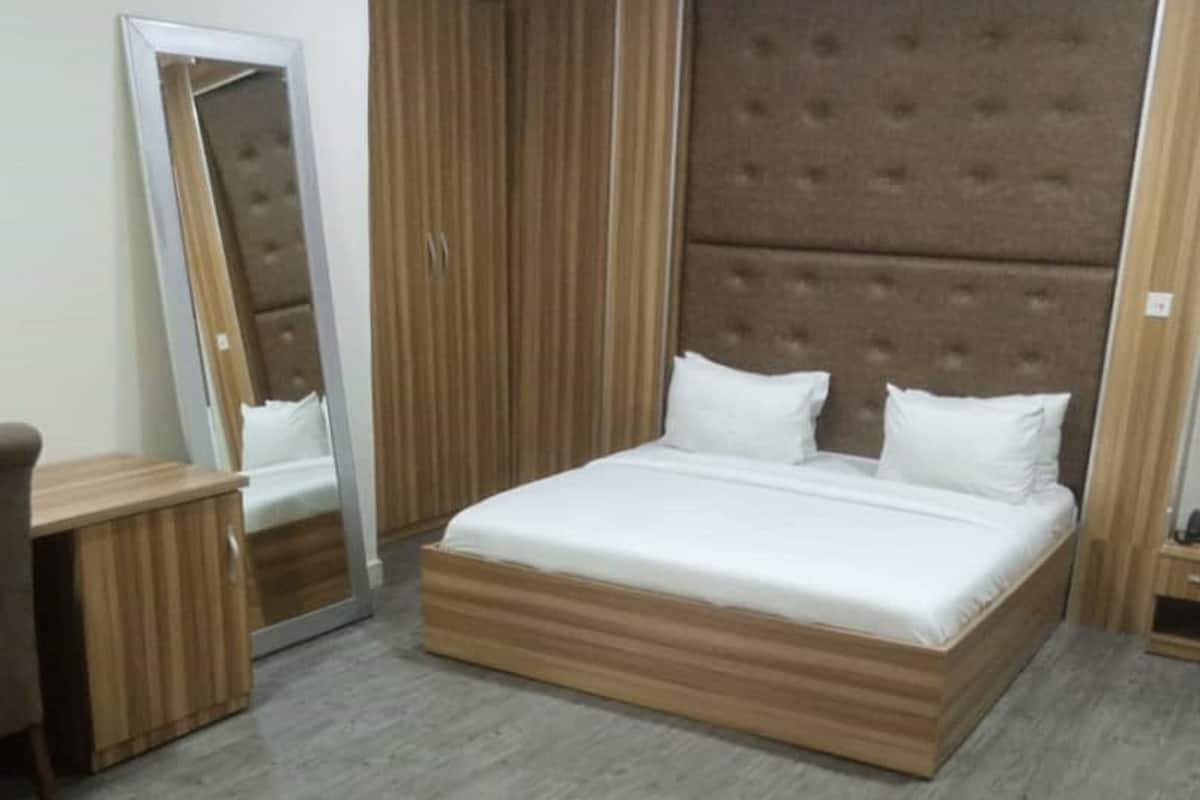A bedroom with a large bed, a mirror, a wardrobe, and a round table.