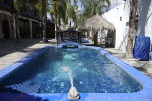 Una piscina con una estructura de techo de paja y un borde de azulejos azules.