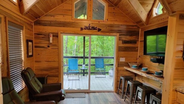 A wooden cabin interior with a living area, a bar, and a deck with chairs. - Juniper: Sleep 5, Tiny Cabin, Pets, Near Park/Lake (Broken Bow)